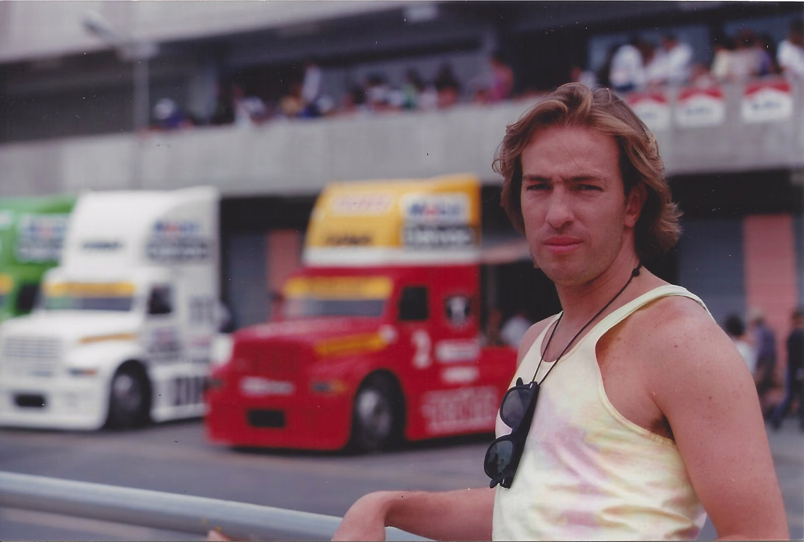 Benny Corral, joven, frente a tractocamiones de carreras en una pista