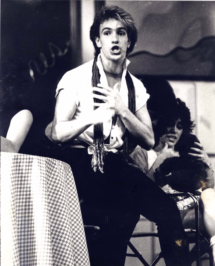 Un actor joven con chaleco gesticula en el escenario