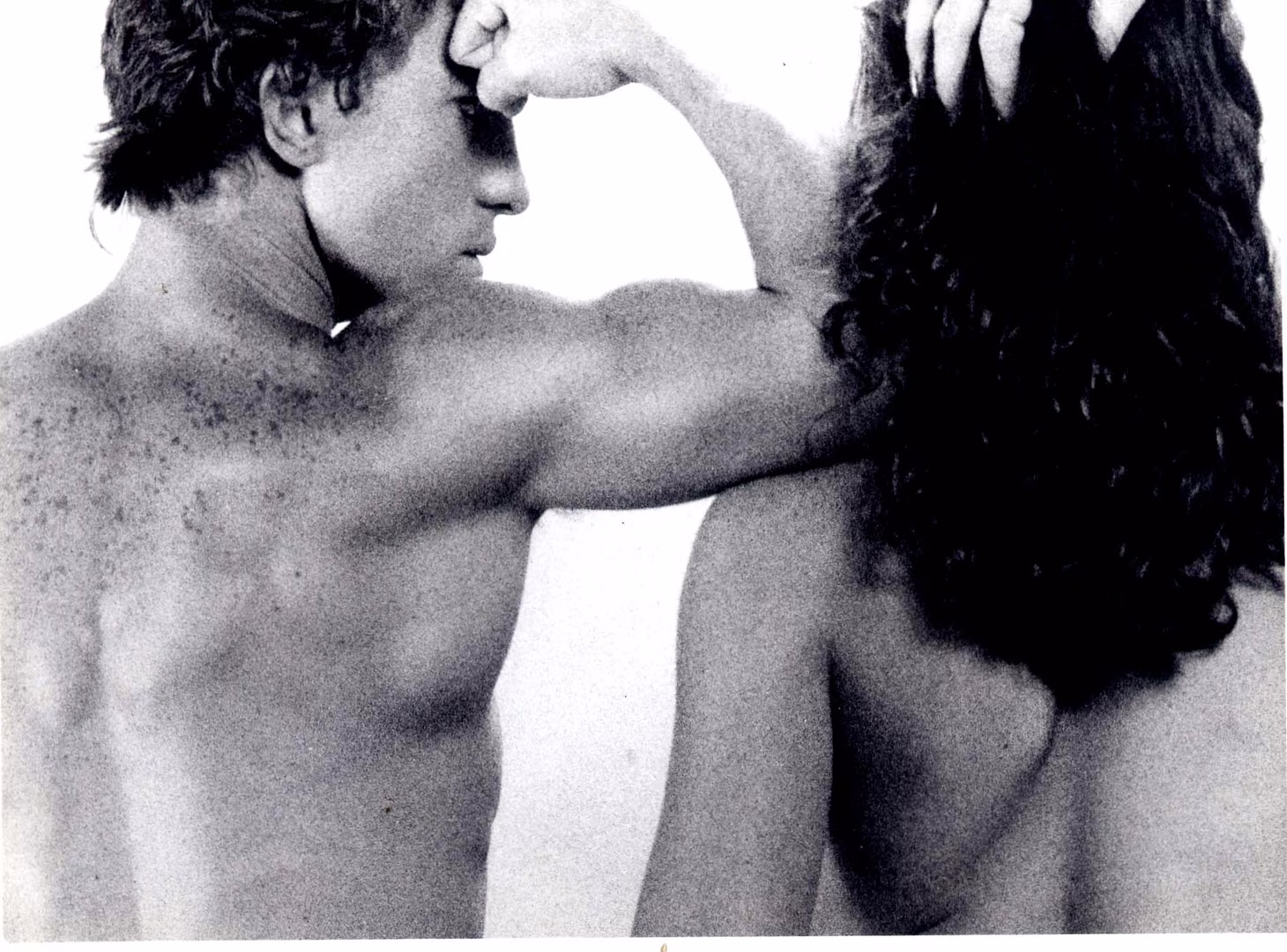Retrato en blanco y negro: un torso y un brazo flexionado junto a una cabellera oscura